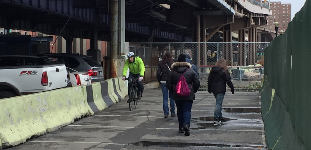 Cyclists and pedestrians must share this narrow, unpaved path shoved between construction to the east and a massive parking lot to the west. Photo: David Meyer