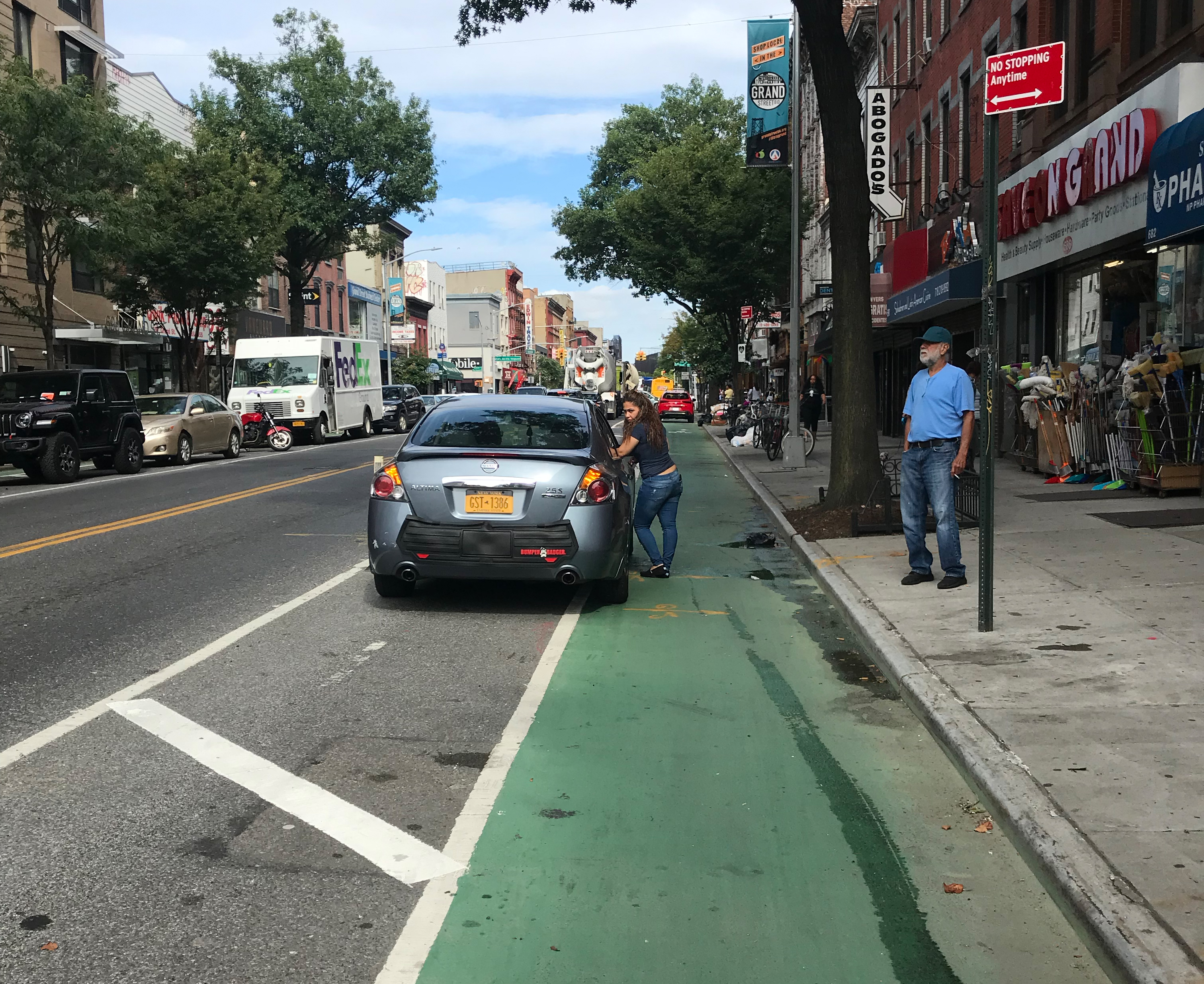 A woman talking to a driver parked in the bike lane. Photo: Julianne Cuba