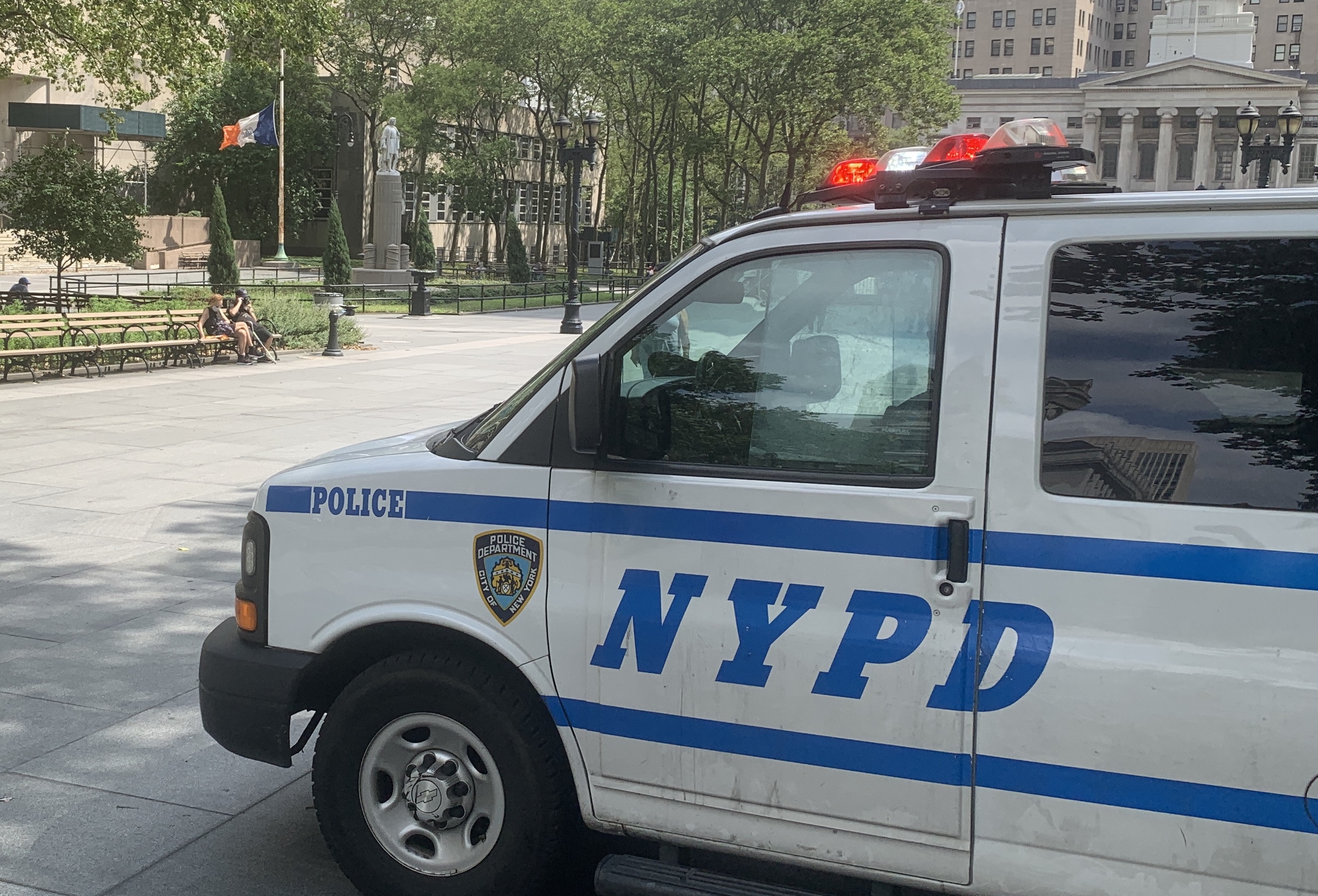 The statue is in the background, under the watchful eyes of the police officers in the van.