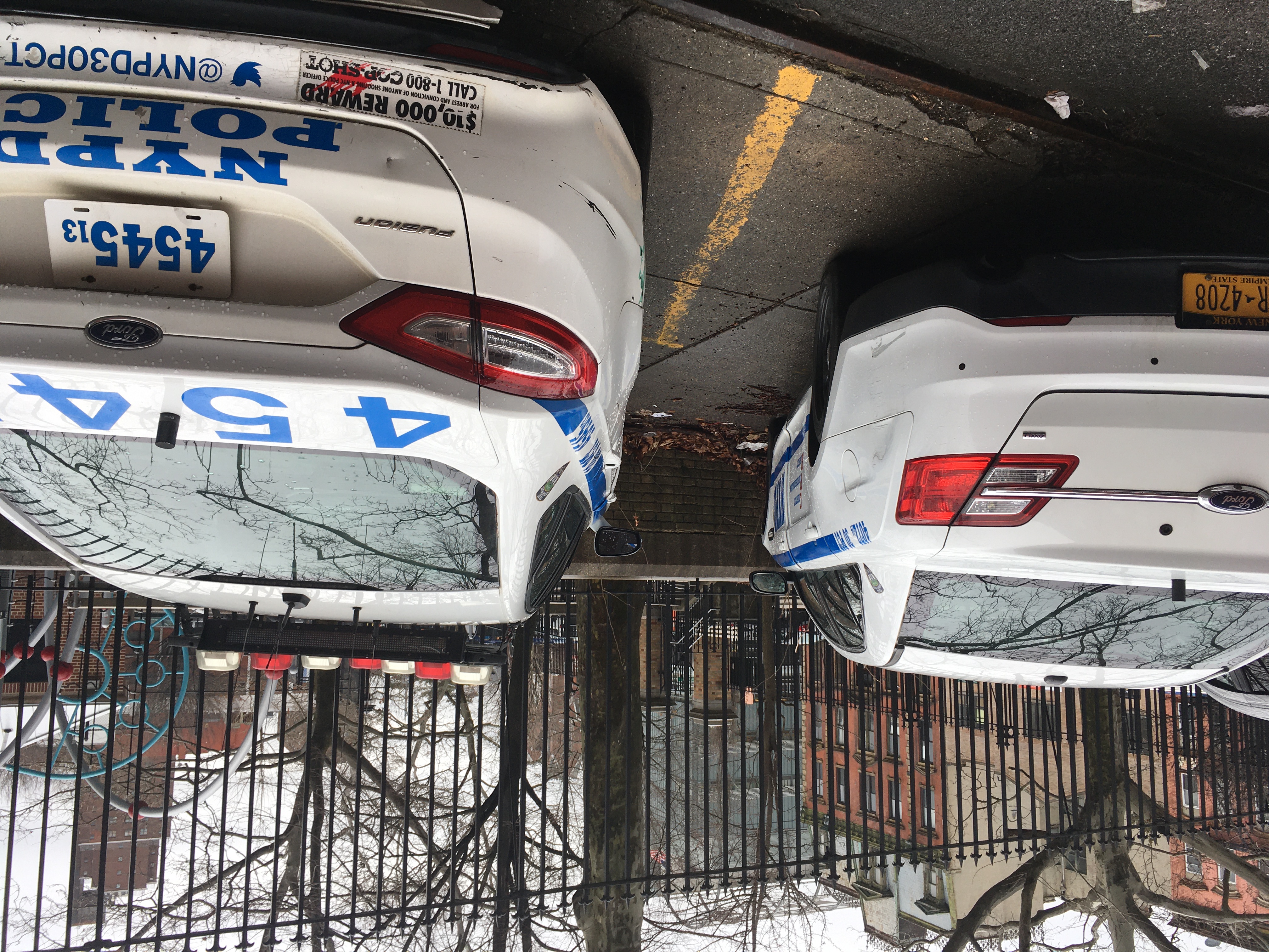 Police cars completely hem in the sidewalk next to Carmansville Playground, rendering it useless for pedestrians. Photo: Eve Kessler