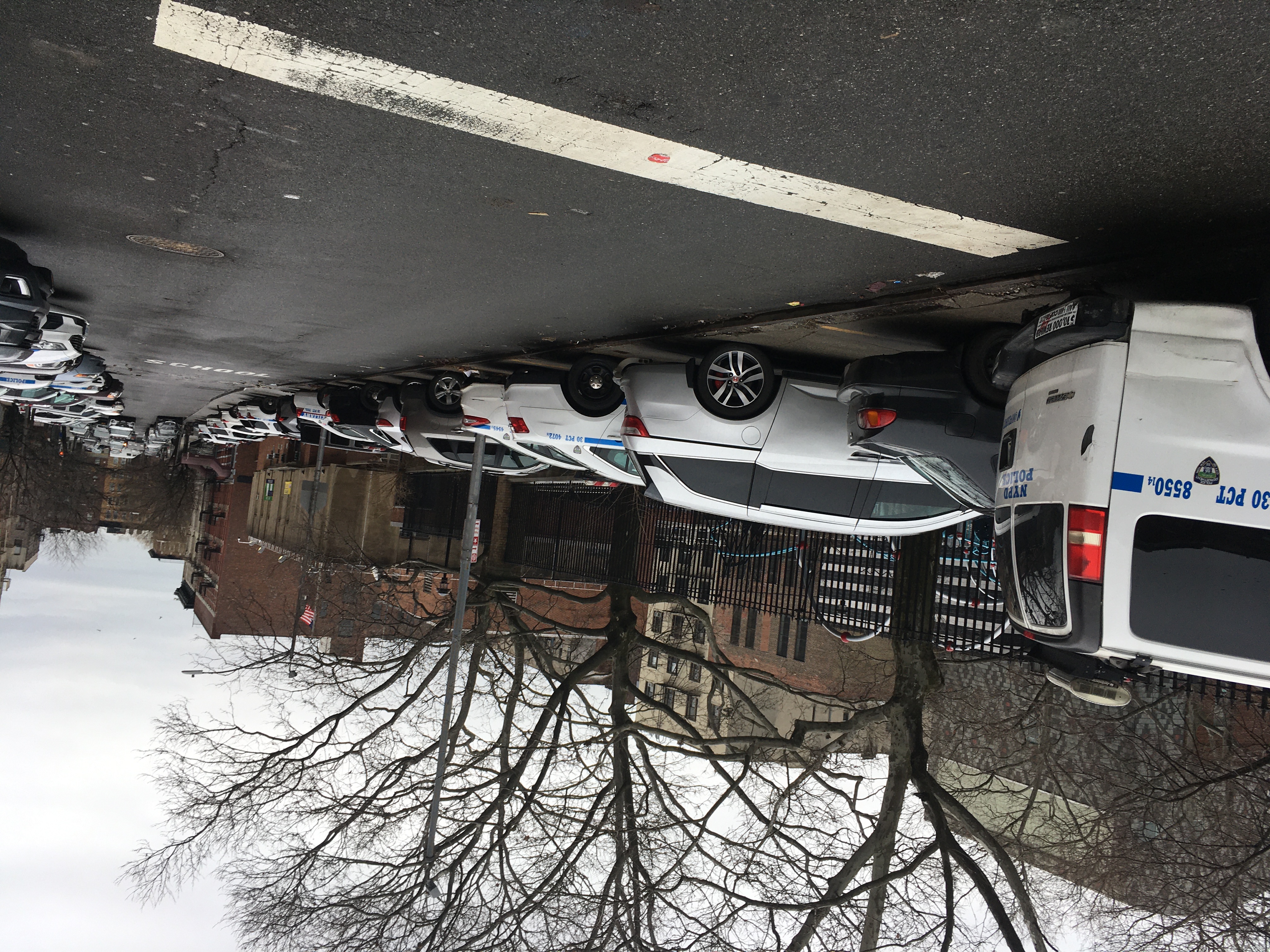 The length of 151st Street in Hamilton Heights, looking east, shows a sewer of police vehicles. The 30th precinct is the yellowish brick building on the left. Photo: Eve Kessler