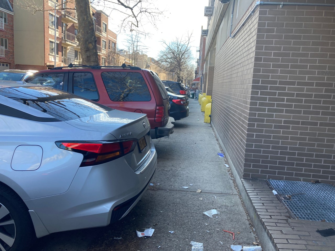 Trash builds up behind cars on the sidewalk outside the 114. Photo: Julianne Cuba